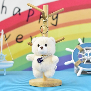 Detail shot of a cute white plush teddy bear keychain featuring a miniature guitar charm
