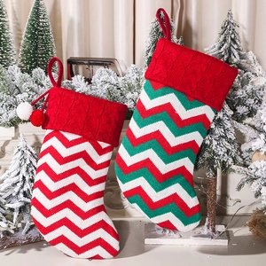Knitted Christmas stockings with red, white, and green patterns hanging by the fireplace