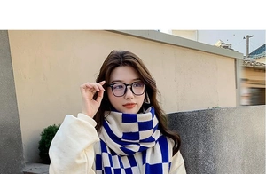 Close-up of blue and white checkerboard knit scarf material with trendy black glasses