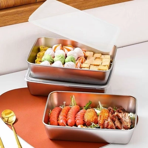 Set of three stainless steel food containers with translucent lids on a wooden table