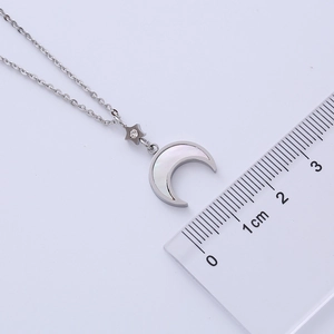 Detailed view of silver star and moon shell necklace with a ruler for size measurement