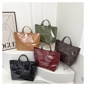 Five glossy vintage tote bags in assorted colors displayed on a white tiered platform
