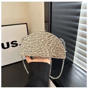 Detail of silver half-moon evening clutch with hammered metallic texture and chain