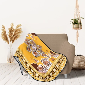 Bright yellow flannel blanket with ethnic mandala pattern on a beige fabric sofa