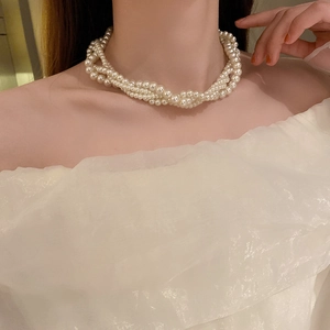 Detailed view of layered baroque pearl choker necklace with intricate woven design on model