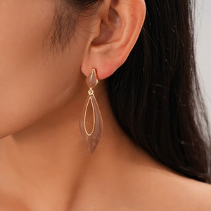 Close-up of a brown drop-shaped earring with gold trim worn by a female model