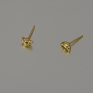 Macro detail of golden croissant stud earrings with French spiral texture finish