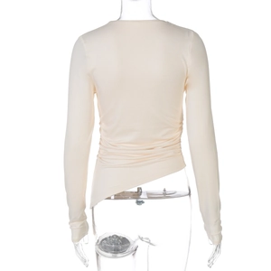 Détail du haut beige cintré à manches longues avec côtés froncés et ourlet asymétrique