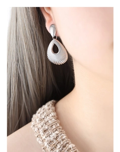 Close-up of retro silver hollow teardrop earrings with radial texture on model