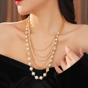 Elegant layered gold necklace with pearls and diamond-set clover charms on model
