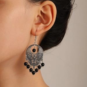Bohemian hollow floral silver alloy earrings with black beads and fringe on a female model