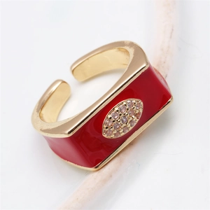 Close-up of golden copper ring with red enamel eye design and micro-inlaid diamonds