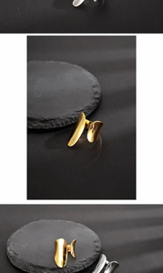 Detailaufnahme minimalistischer Gold- und Silberringe auf texturierten schwarzen Steinen