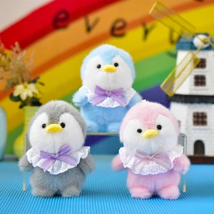 Close-up detail of three colorful plush penguin dolls with lace collars and bows.