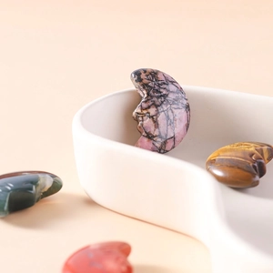 Hand-carved natural crystal moon faces in rose quartz and tiger eye on a ceramic tray