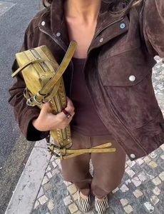 Dettaglio di una giacca di camoscio marrone con borsa verde borchiata e scarpe zebrate