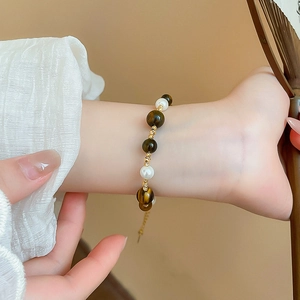 Detailed view of beaded bracelet with brown tiger eye stones, pearls and gold spacers