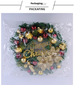 Detail of Christmas wreath with red and gold baubles in transparent packaging