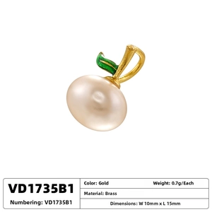 Macro view of cherry-shaped brass charm with white pearl and green enamel leaf detail