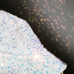 Detailed macro view of high-density iridescent sequins on a white bucket hat surface