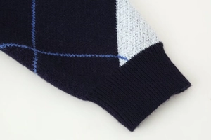 Detailed close-up of navy blue argyle knit sweater cuffs with soft ribbed texture