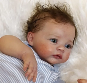 Close-up of Meadow reborn doll with 3D skin texture, blue eyes and brown hair