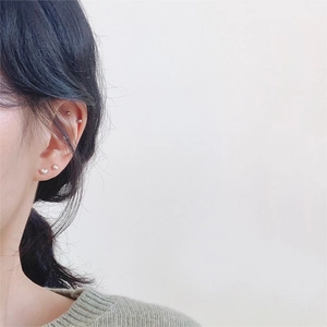 Close-up of minimalist sterling silver ball stud earrings worn on different ear lobe positions