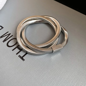 Detailed macro view of triple-layered silver spiral snake chain bracelet with metal clasp