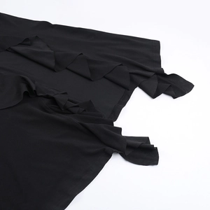 Détail d'une robe noire à une épaule avec des volants et des rubans fluides élégants