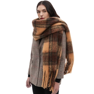 Brown and black plaid oversized scarf with tassels worn by a model on a white background