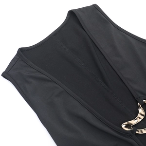 Detail of deep black sleeveless dress showing golden wavy metal buckle and refined stitching