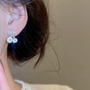Close-up of elegant cherry pendant earrings with sparkling zircons worn by a model