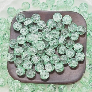 Macro shot of green round glass beads with ice crackle texture on a wooden tray