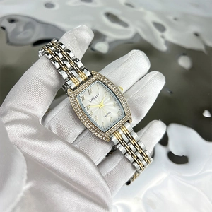Close-up of tonneau emerald quartz watch with crystal bezel and two-tone metal strap