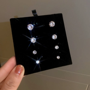 Detailed view of four pairs of magnetic zirconia stud earrings on black velvet cards