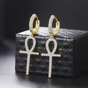 Detail of gold-plated Ankh cross earrings with cubic zirconia on black jewelry box