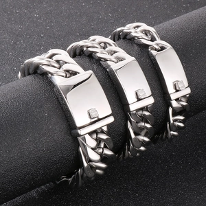 Detailed view of silver Cuban link bracelets with rectangular clasps on a dark display