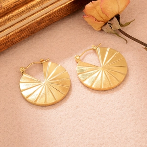 Détail de boucles d'oreilles dorées en forme de U avec texture radiale sur fond vintage
