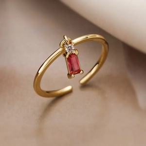 Macro shot of gold plated adjustable open ring with red rectangle and clear round zircon stones