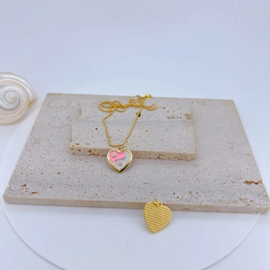 Close-up of gold heart pendant with pink Tai Chi pattern and zircon inlay on stone