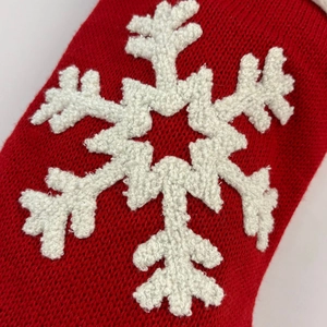 Macro shot of red knitted Christmas stocking texture with white snowflake patterns
