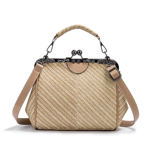 Detail of beige woven tote bag with bronze kiss-lock closure and leather handles