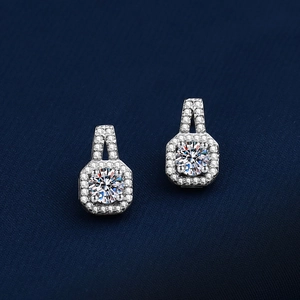 Macro view of geometric octagonal earrings with moissanite on dark blue silk fabric