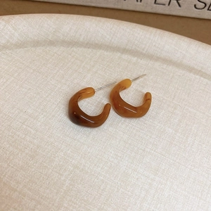 Gros plan de boucles d'oreilles en acrylique ambré sur une assiette texturée