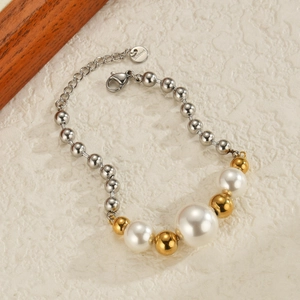 Detail view of stainless steel bead bracelet with white pearls on textured background
