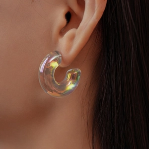 Macro detail of thick iridescent acrylic C-shaped earrings showing colorful light refraction