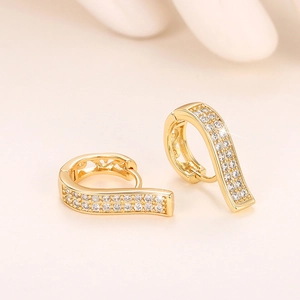 Macro shot of gold curved drop earrings with pavé white zircons in a luxury finish