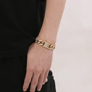 Detail eines goldenen Panzerarmbands mit Strasssteinen am Handgelenk eines Mannes