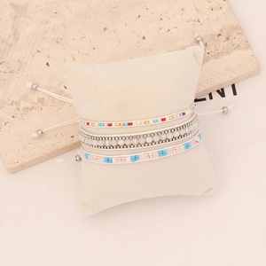 Close-up of Bohemian layered bracelets with colorful beads on a cream jewelry pillow