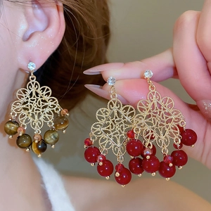 Macro detail of vintage hollow metal earrings with tiger eye and red crystal beads
